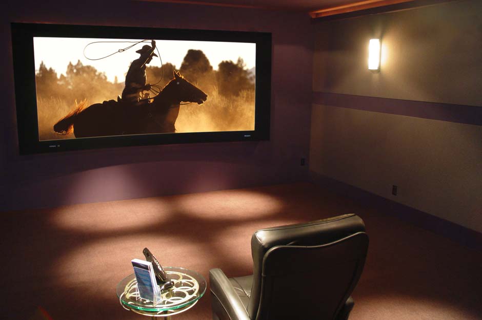 RESIDENTIAL Interior - Home theater installation in a dimly lit room. Used ambient lighting with supplemental placed and reflective lighting. Retouched screen overlay with recreated screen edge reflection highligts.